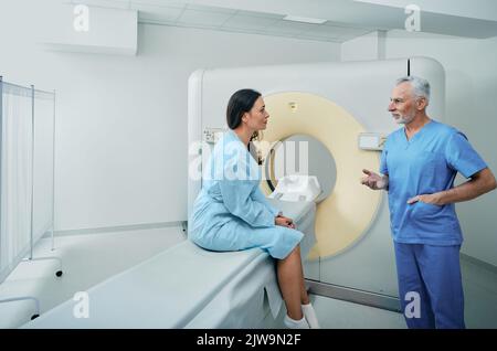 Computertomographie. Medizinisches Fachpersonal, das vor der Durchführung der CT-Untersuchung mit einer Patientin in der Radiologie des Krankenhauses spricht Stockfoto