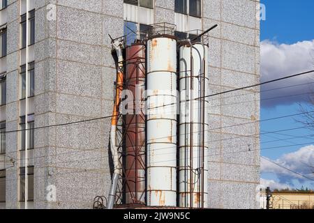 Industrierohre vom Ende des Gebäudes, rostige alte Rohre an der Seite der Fassade des Hauses Stockfoto