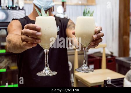 Der Barkeeper zeigt dem Gast das Getränk, das er gerade zubereitet hat. Nachtclub- oder Partyatmosphäre. Edle Getränke. Nachtleben Stockfoto