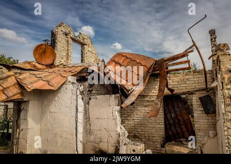 Ruinen eines privaten Hauses. Verbranntes Haus. Eine rostige Satellitenschüssel. Ruiniert das Leben. Überreste des Gebäudes. Krieg in der Ukraine. Verbranntes Haus. Rakete getroffen. Stockfoto