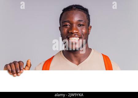 afroamerikanischer Student mit Rucksack im Studio lächelt mit einem weißen Lächeln auf die Kamera Stockfoto