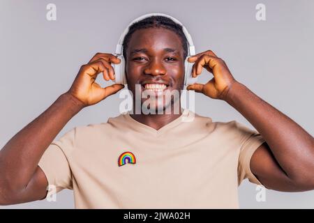 mexikanischer Mann mit weißem Kopfhörer, der Musik in beigefarbenem T-Shirt hört Stockfoto