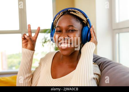 lateinamerikanische hispanische Frau hört Musik, während sie auf dem Sofa im Wohnzimmer sitzt Stockfoto