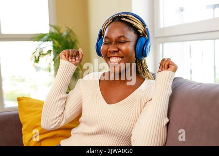 lateinamerikanische hispanische Frau hört Musik, während sie auf dem Sofa im Wohnzimmer sitzt Stockfoto