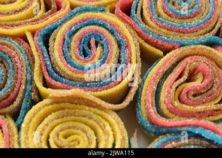 Kaublättrige Marmelade in Streifen mehrfarbig gelb blau rot grün gerollt zu Schnecken Nahaufnahme. Süßigkeiten Tag gesunde Leckereien. Dessert mit Agar-Gelatine. Stockfoto