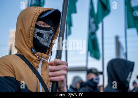 Warszawa, Polen. 11.. November 2021. Ein maskierter Mann hält während des Unabhängigkeitsmarsches eine Flagge. Am 11. November wird der unabhängigkeitsmarsch jährlich von radikalen nationalen Kreisen organisiert. Der marsch weckt in der Gesellschaft viele Ängste und Emotionen aufgrund der Verluste, die Warschau nach diesem marsch in den vergangenen Jahren erlitten hat, kamen an diesem Tag Polizeieinheiten aus allen Polen in die Hauptstadt, um Ordnung und Sicherheit der Demonstranten zu gewährleisten. (Foto von Pawe? Wróblewski/SOPA Images/Sipa USA) Quelle: SIPA USA/Alamy Live News Stockfoto