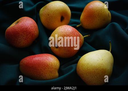 Gelb-orange Birnen auf einem dunkelgrünen Tisch. Stockfoto
