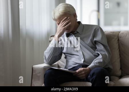 Verzweifelt depressiver älterer Mann, der schlechte schockierende Nachrichten erhalten hat Stockfoto