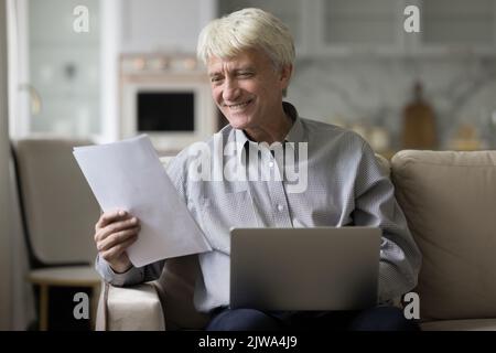 Glücklich reifen grauhaarigen Mann arbeitet von zu Hause aus Stockfoto