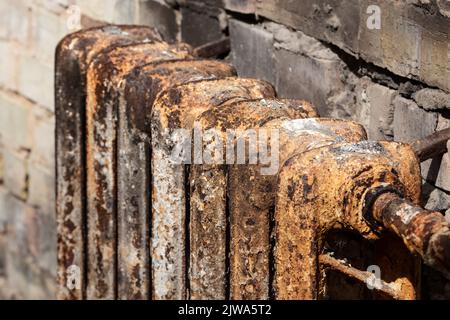 Eine rostige gusseiserne Batterie in einem ausgebrannten Haus. Akku aus Gusseisen. Heizgerät. Der Ort des Feuers. Verbrannte Wohnung. Feuersbrunst. Sitz o Stockfoto