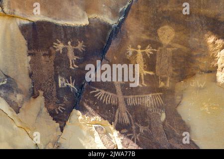 Felskunst der Petroglyphen in Legend Rock State Archaeological Site, Wyoming - Diese Gruppe von en toto gepeckten Figuren enthält einen thunderbird, der eine Associa ist Stockfoto