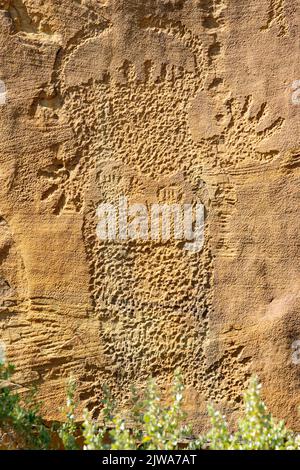 Felskunst der Petroglyphen in Legend Rock State Archaeological Site, Wyoming - eine en toto gepeckte anthropomorphe Form, die auf einer Sandsteinplatte sichtbar ist. Stockfoto