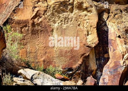 Felskunst der Petroglyphen in Legend Rock State Archaeological Site, Wyoming - mehrere skizzierte en toto pickte und gestickte anthropomorphe und zoomorphe f Stockfoto