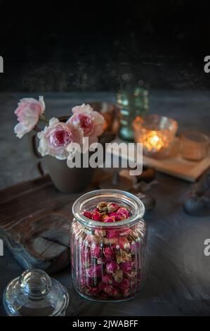Auf einem Holztisch steht ein durchsichtiges, geriffeltes Glas aus rosa Tee. Teestunde, gemütliche Atmosphäre. Küche Stillleben mit rosa Blumentee mit warmem Licht in der Stockfoto