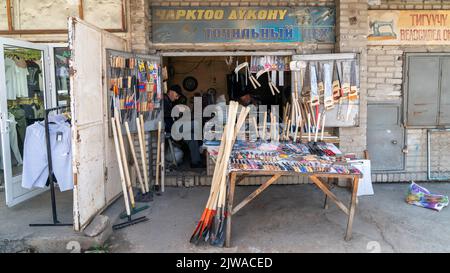 Osh, Kirgisistan - Mai 2022: Lokaler Baumarkt in Oshs Hauptmarkt im Stadtzentrum. Zwei ältere Männer sitzen in einem alt aussehenden Laden. Stockfoto