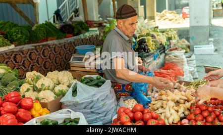 Osch, Kirgisistan - 2022. Mai: Auf dem Osch-Markt verkauft ein lokaler Händler frisches Obst und Gemüse von einem Stand aus. Stockfoto