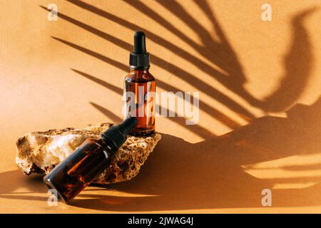 Kosmetische Tropfflasche Stein Podium Sockel. Brauner Hintergrund mit harten Schatten vom Pflanzenzweig Stockfoto