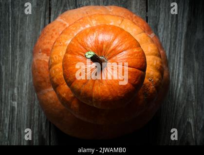 Stapel Halloween Kürbisse auf Holzplanken, Draufsicht auf orangen Gemüsehurm auf dunklem Holzboden oder Tisch. Thanksgiving, Kürbis, Essen, Natur, pa Stockfoto