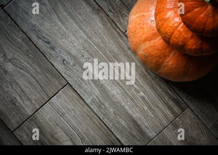 Stapel von Kürbissen auf Holzplanken Hintergrund für Halloween-Thema. Blick von oben auf den Turm mit orangefarbenem Gemüse auf Holzboden und Platz. Halloween, danke Stockfoto