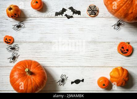 Halloween Hintergrund, Draufsicht. Kürbisse und Süßigkeiten auf weißem Holztisch, flach liegend. Rahmen von Halloween orange Lebensmittel und Dekorationen auf Holzplanken mit Stockfoto