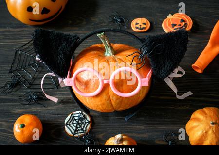 Halloween Stillleben auf Holztisch, Kürbisse und Süßigkeiten auf dunklem Holz. Fröhlicher orangefarbener Kürbis mit Gläsern, abwechslungsreichen Halloween-Speisen und Dekorationen. Lif Stockfoto