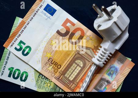 Netzstecker und Euro-Geld, inländisches Stromkabel auf europäischen Banknoten, Draufsicht. Energiekrise in Europa, teurer Eigenstrompreis. Konzept Stockfoto