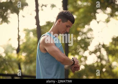 Mann Läuferin in Sportbekleidung, der die Zeit auf der Smartwatch überprüft Stockfoto