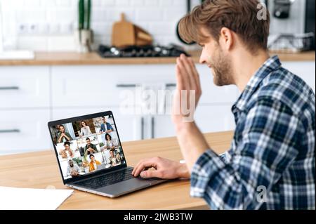 Seitenansicht des kaukasischen Mannes, der zu Hause in der Küche sitzt und durch eine Videokonferenz mit einer Gruppe von multirassischen erfolgreichen Kollegen spricht, besprechen Unternehmensförderung, Werbung, Finanzstrategie, neues Projekt Stockfoto