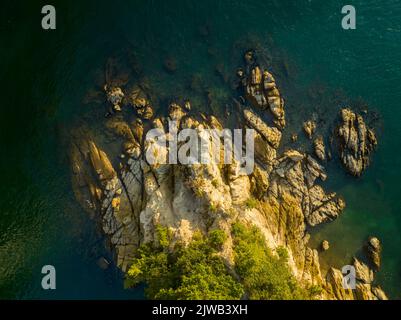 Luftaufnahme von zerklüfteten Felsen ins Wasser an der Küste Stockfoto