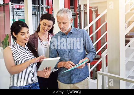 Sehen Sie sich das an... drei Kollegen, die sich ein digitales Tablet ansehen. Stockfoto