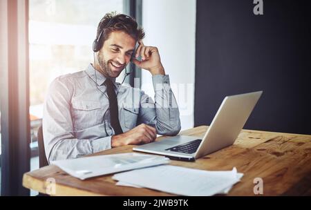 Er steht für zuverlässigen Kundenservice. Ein Callcenter-Agent, der in einem Büro an einem Laptop arbeitet. Stockfoto