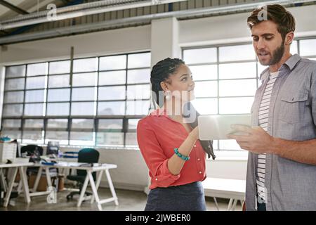 Eine neue Geschäftsmöglichkeit im Internet teilen: Zwei Kollegen nutzen gemeinsam ein digitales Tablet in einem modernen Büro. Stockfoto