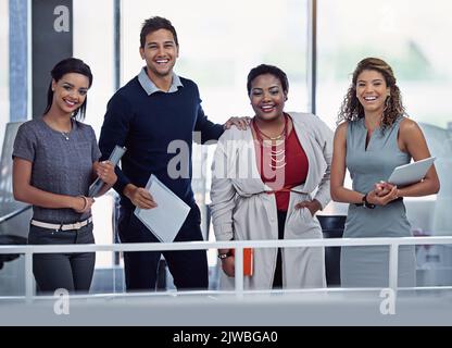 Unser Erfolg hängt davon ab, dass wir alle zusammenarbeiten. Porträt einer Gruppe lächelnder Kollegen, die in einem Büro zusammenarbeiten. Stockfoto