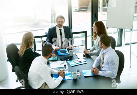 Ein Team von Führungskräften, das eine formelle Sitzung in einem Sitzungssaal hat. Stockfoto