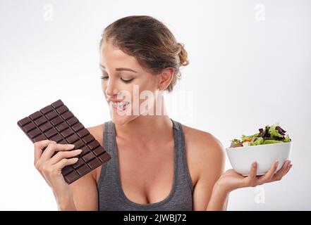 Shes ein Liebhaber von Schokolade. Studioaufnahme einer attraktiven jungen Frau, die von etwas Süßem verlockt wird. Stockfoto