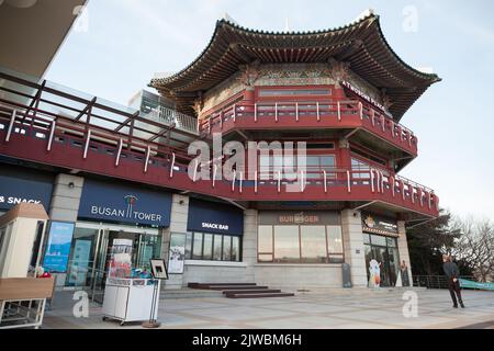 Busan, Südkorea - 14. März 2018: Touristenpavillon am Eingang zum Busan Tower im Yongdusan Park. Gewöhnliche Menschen gehen die Straße entlang Stockfoto