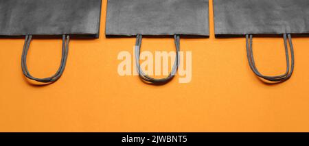 Einkaufstaschen auf orangefarbenem Hintergrund. Angebot „Black Friday“ Stockfoto