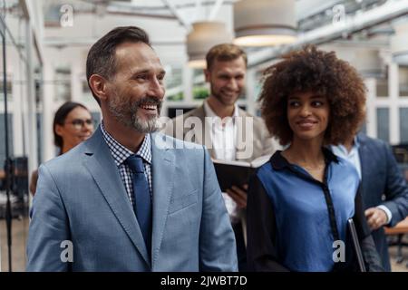 Multiethnische Gruppe von Geschäftsleuten, die während der Pause im Büro stehen. Teamwork-Konzept Stockfoto