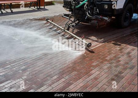 Eine spezielle Maschine wäscht Stadtwege und Straßen mit Wasser Stockfoto