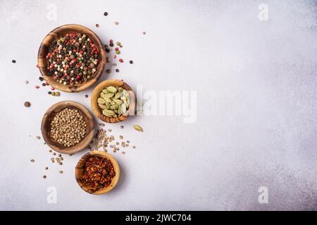 Draufsicht auf Mix helle Gewürze oder Gewürze in kleinen Holzschüsseln als Zutat für gesunde Lebensmittel auf grauem Beton-Hintergrund Stockfoto