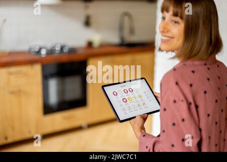 Frau steuert Heimgeräte mit einem digitalen Tablet zu Hause Stockfoto