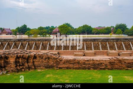 Hochwasser am Fluss in Ayutthaya, Thailand im Wat Chaiwatthanaram während des Sonnenuntergangs in Ayutthaya, Thailand während der Monsun-Regenzeit, Hochwasserschutzmauer am Fluss Stockfoto