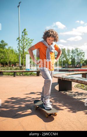 Ruhiger, fokussierter Jugendlicher, der auf das Skateboard steigt Stockfoto