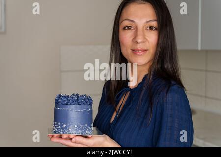 Der Konditor hält einen Kuchen. Die Hände der Womans halten frisch gebackenen Kuchen Stockfoto
