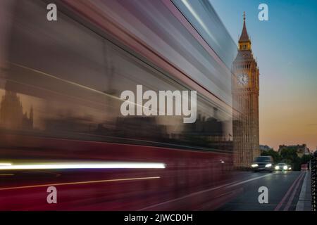 Der Londoner Bus fährt im Morgengrauen über die Westminster Bridge. Das Parlament ist hinter sich Stockfoto