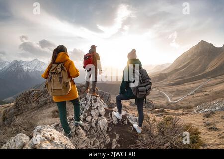 Eine Gruppe von Wanderern oder Touristen mit Rucksäcken spaziert in den Bergen bei Sonnenuntergang Stockfoto