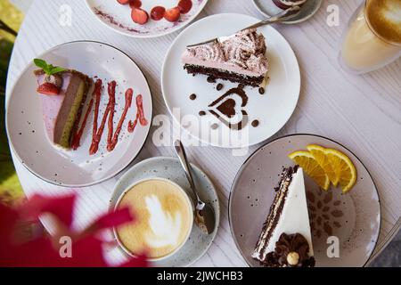 Natürliche vegane, gesunde, geschichtete Desserts, ein Stück Kuchen mit frischen Früchten und Beeren draußen. Feier, Süßigkeitenauswahl auf der Terrasse. Stockfoto