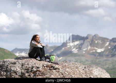 Wanderer auf dem Gipfel eines Berges, der die Aussicht auf einem Felsen betrachtet Stockfoto
