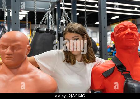 Nettes Teenager-Mädchen umarmt zwei Gummi-Boxen Dummies. Extremsport Stockfoto