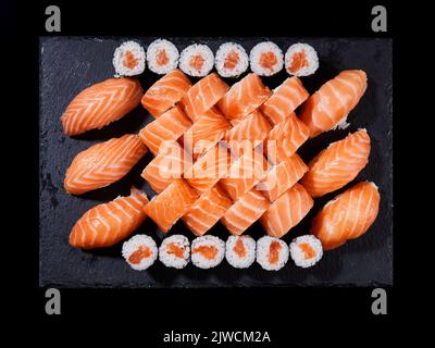 Draufsicht Sushi rollt philadelphia, Sashimi und Maki auf einem schwarzen Schieferteller. Stockfoto